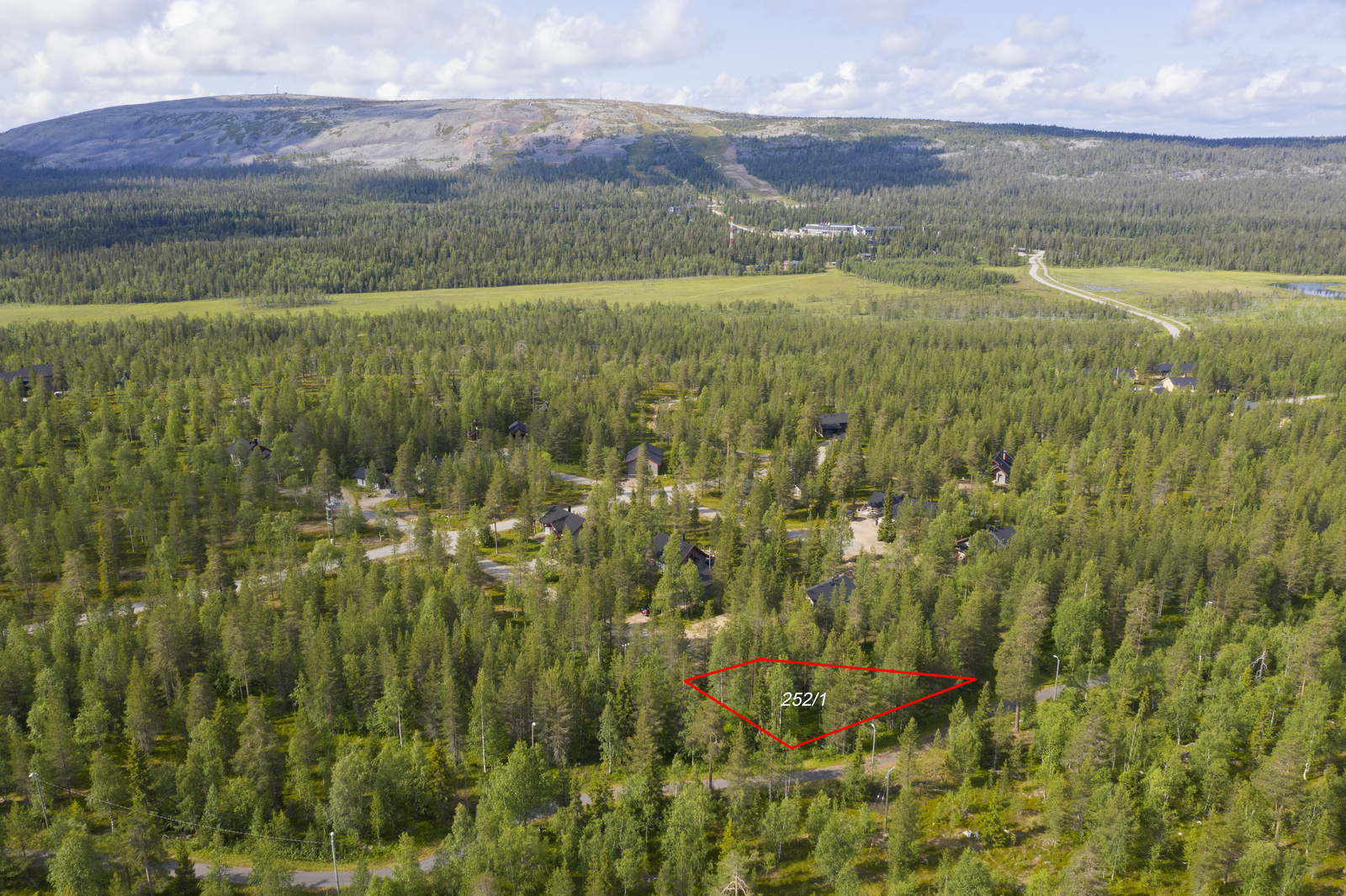 Tontin kaava piirrettynä metsän ylle mökkialueella. Horisontissa kohoaa Luostotunturi. Ilmakuva.