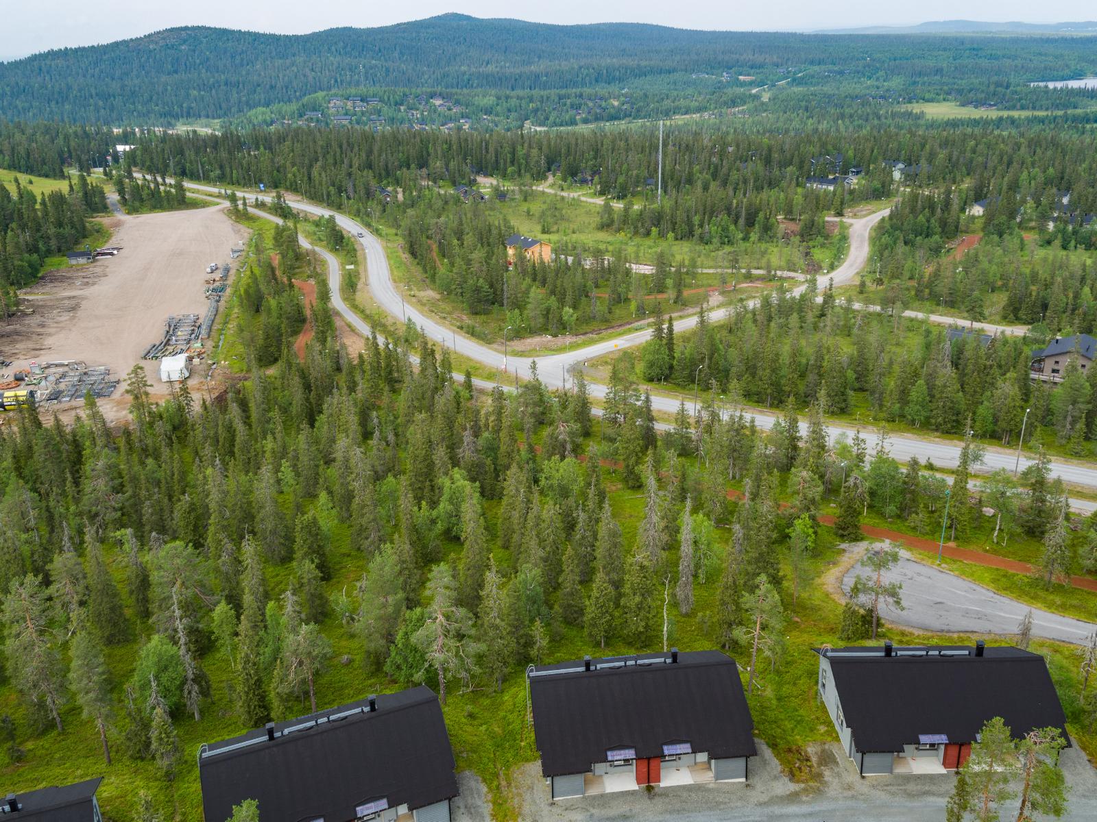 Matkailukeskuksen mökkialueella risteilee teitä. Horisontissa kohoaa tunturimaisema. Ilmakuva.