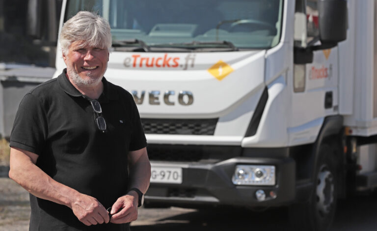 Mies seisoo valkoisen kuorma-auton edessä.