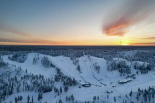 Talvinen ilmakuva tunturikeskuksen laskettelurinteistä, hyppyrimäistä ja hiihtostadionista.