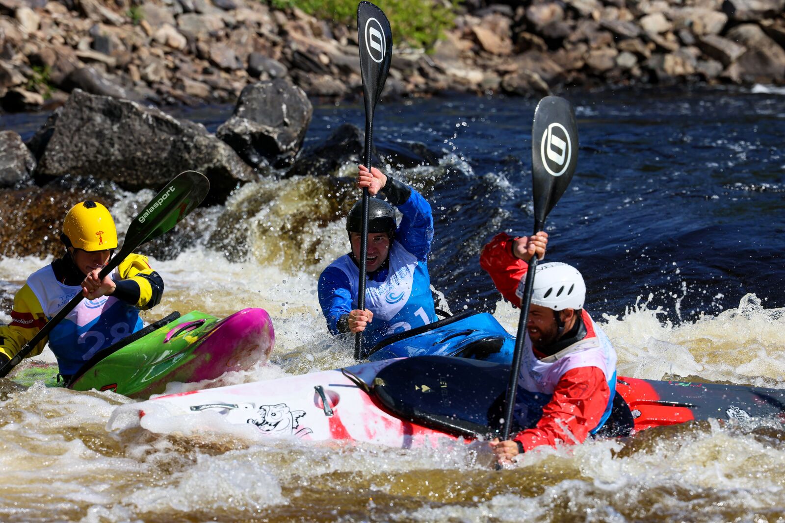 Kolme koskimelojaa etenee koskessa.