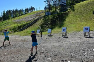 Kaksi henkilöä on harjoittelemassa jousiammuntaa harjoitteluradalla.