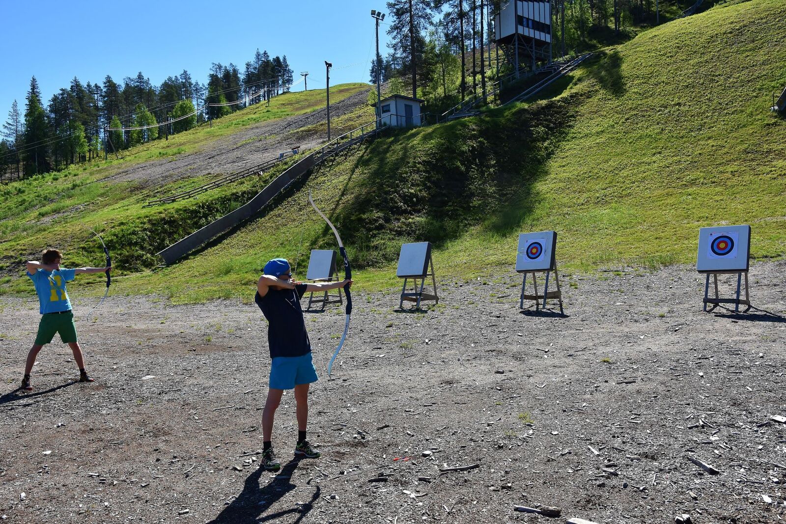 Kaksi henkilöä on harjoittelemassa jousiammuntaa harjoitteluradalla.