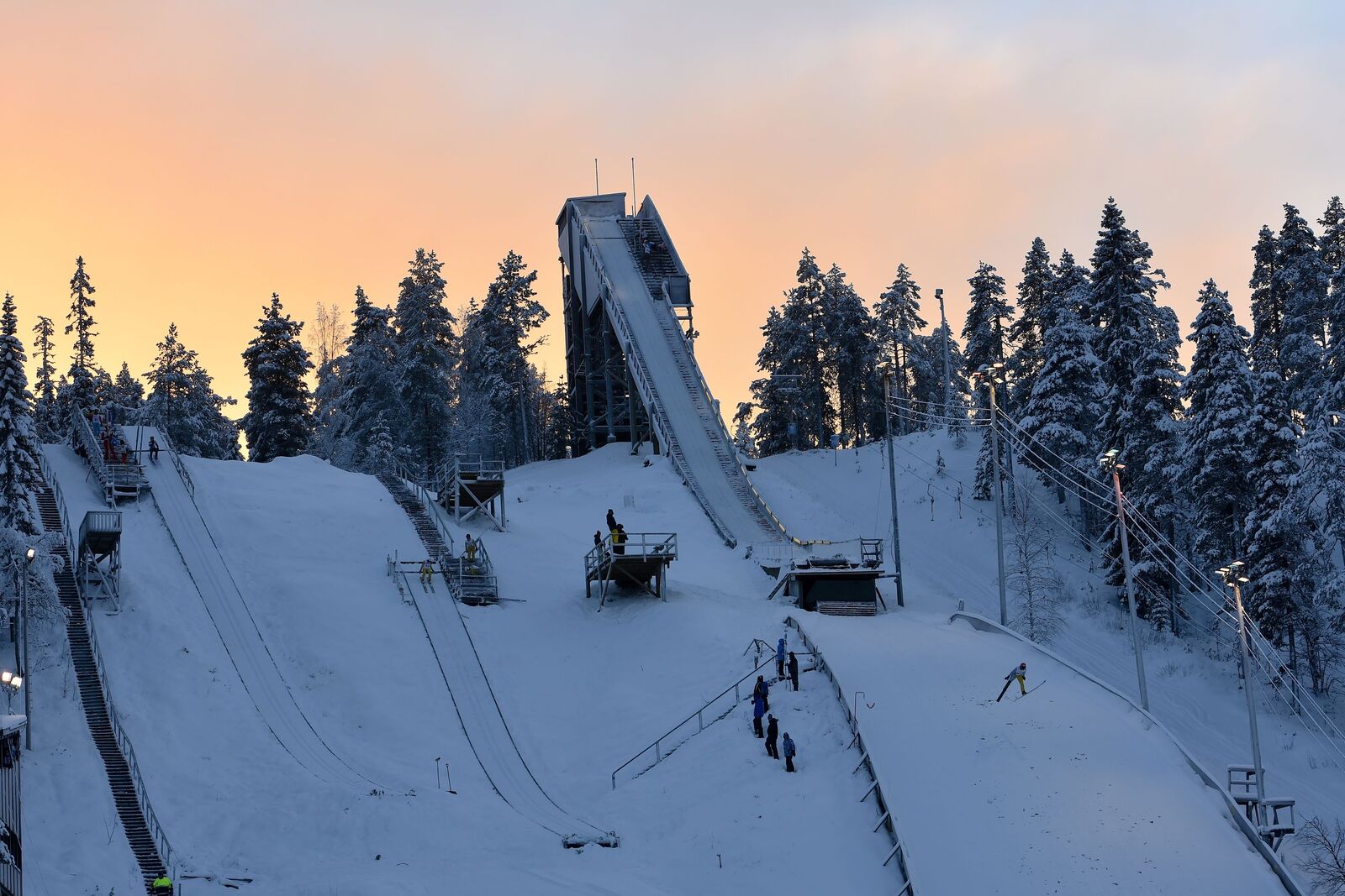 Talvinen auringonlaskun värityksessä oleva hiihtokeskuksen hyppyrimäki.