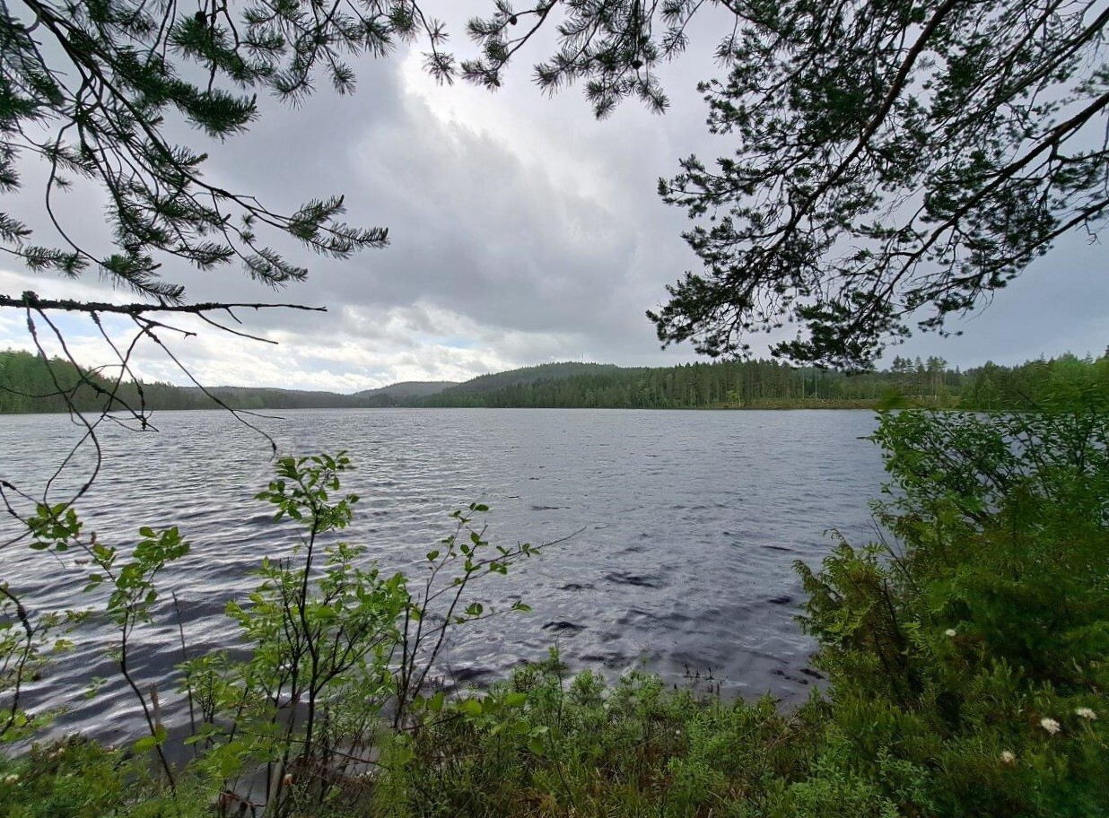 Harmaita sadepilviä taivaalla järven yllä, kaukana edessä näkyy vastaranta.