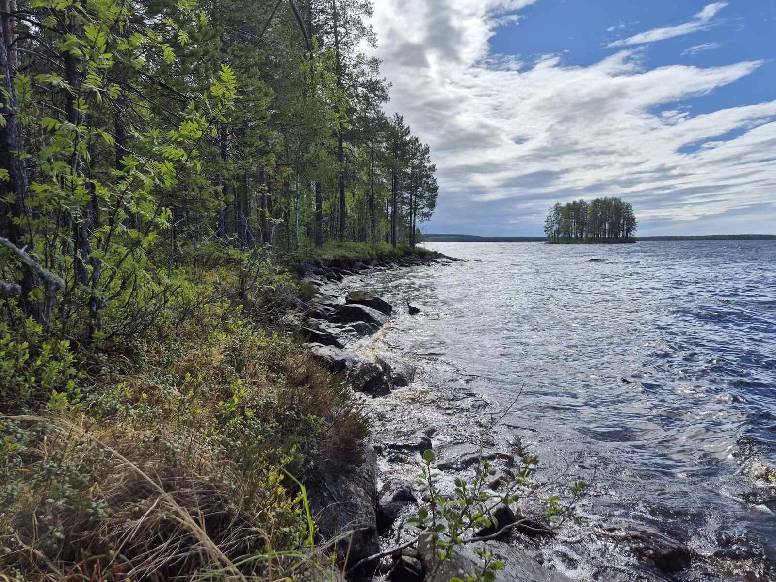 Tontin kivistä rantaa, kauempana järvellä näkyy saari.