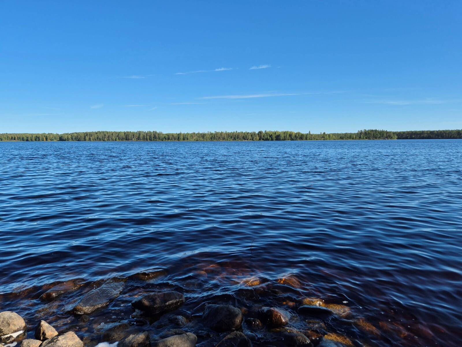 Maisema järvelle, ranta on kivikkoinen, vastaranta näkyy kaukaisuudessa.